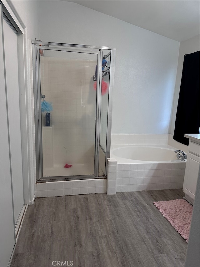 bathroom with shower with separate bathtub, lofted ceiling, hardwood / wood-style flooring, and vanity