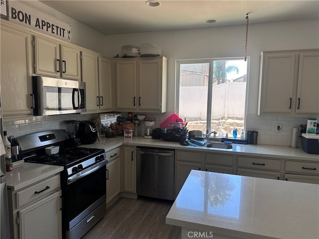 kitchen with appliances with stainless steel finishes, tasteful backsplash, dark wood-type flooring, and sink