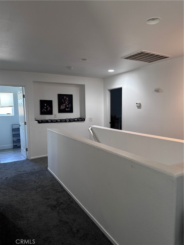 hallway featuring dark colored carpet