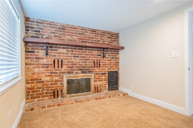 unfurnished living room featuring a brick fireplace and carpet floors