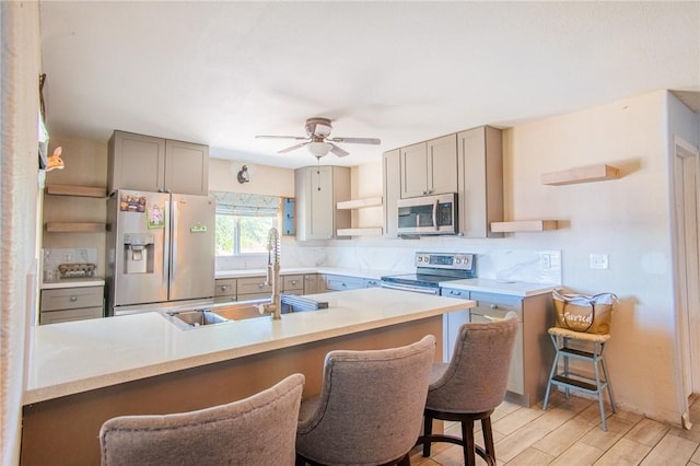 kitchen featuring open shelves, stainless steel appliances, gray cabinetry, a sink, and wood tiled floor