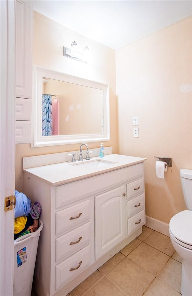 bathroom with baseboards, toilet, tile patterned flooring, and vanity
