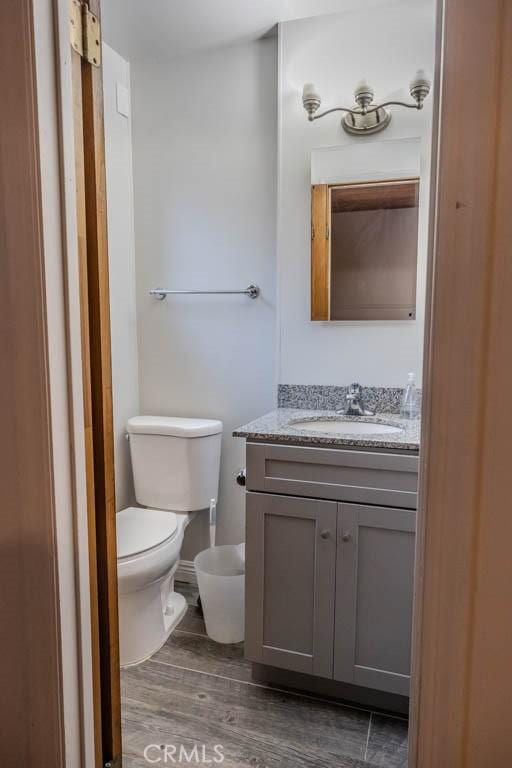 bathroom featuring wood-type flooring, vanity, and toilet