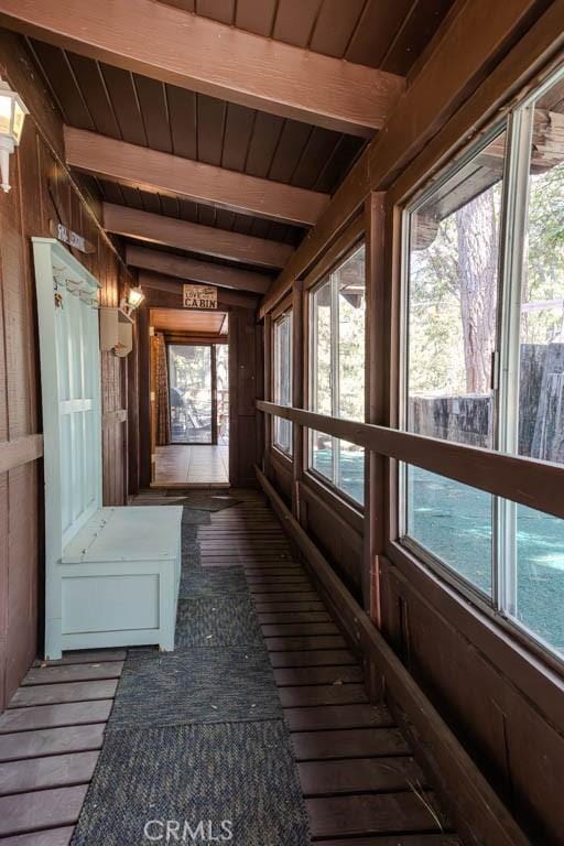 unfurnished sunroom with a wealth of natural light, beamed ceiling, and wood ceiling