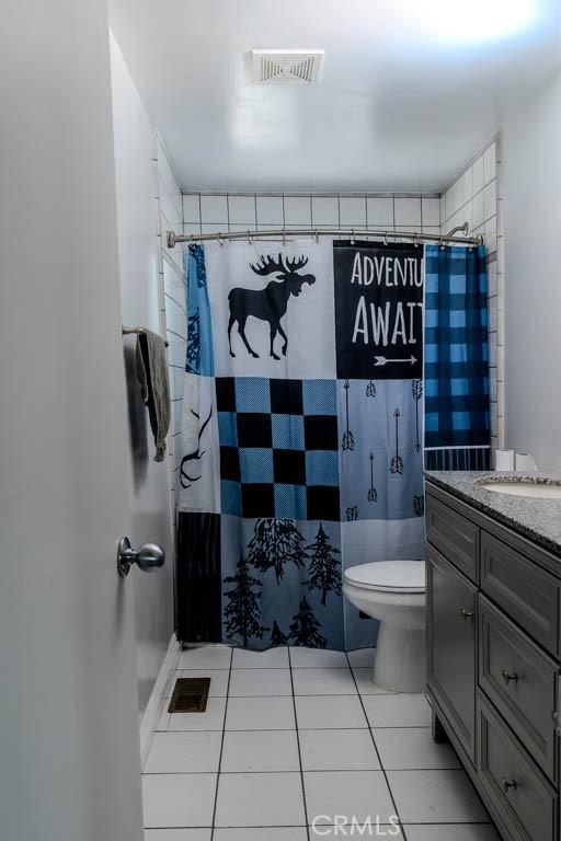 bathroom featuring tile patterned flooring, vanity, toilet, and walk in shower