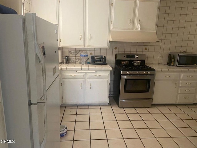 kitchen featuring tile countertops, appliances with stainless steel finishes, and white cabinetry