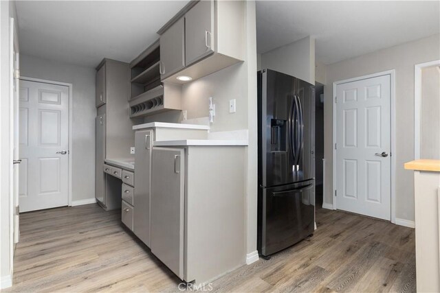 kitchen with gray cabinets, white refrigerator, light wood-type flooring, and fridge with ice dispenser