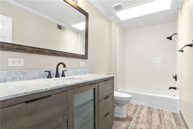 full bathroom with vanity, tiled shower / bath, hardwood / wood-style flooring, toilet, and ornamental molding