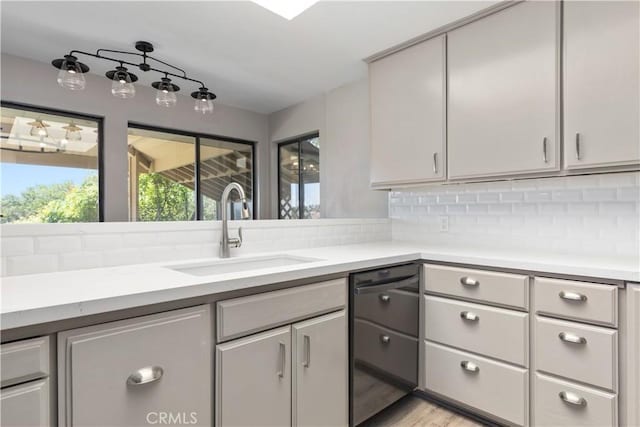 kitchen featuring gray cabinetry, dishwasher, sink, light hardwood / wood-style flooring, and decorative backsplash