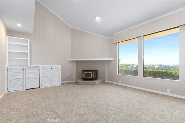 unfurnished living room with carpet, a wood stove, and crown molding