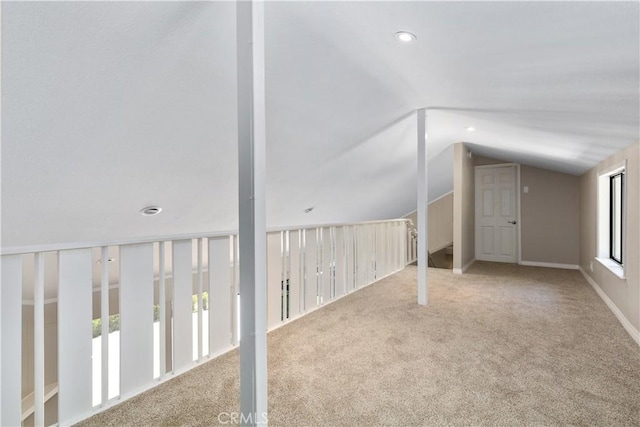 additional living space featuring light carpet and vaulted ceiling