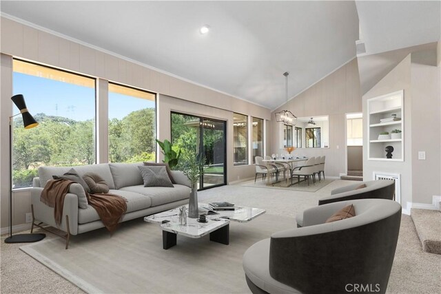 carpeted living room with high vaulted ceiling and an inviting chandelier