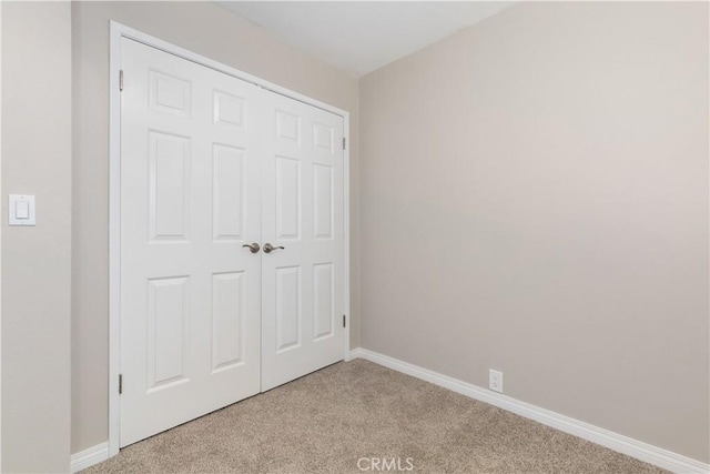 unfurnished bedroom featuring light carpet and a closet