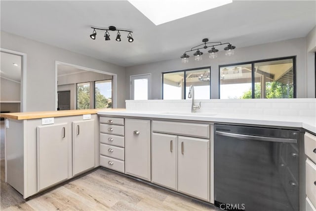 kitchen with dishwasher, backsplash, white cabinets, sink, and light hardwood / wood-style floors