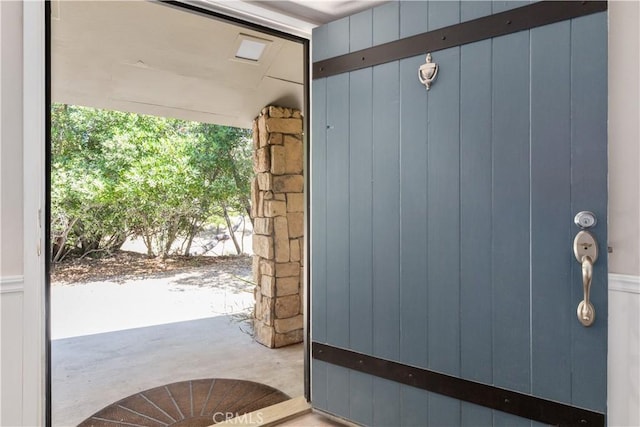 doorway with concrete floors and wood walls