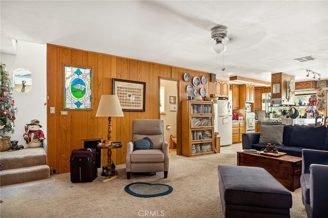 carpeted living room with ceiling fan and wooden walls