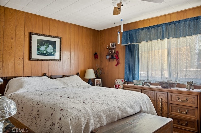 bedroom featuring ceiling fan and wood walls