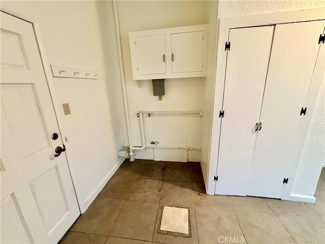 clothes washing area with cabinets and light tile patterned floors