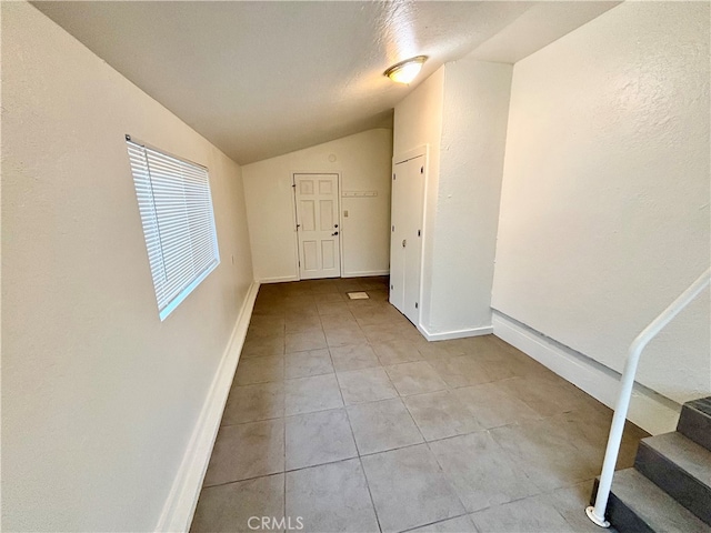 interior space featuring light tile patterned flooring, vaulted ceiling, and a textured ceiling