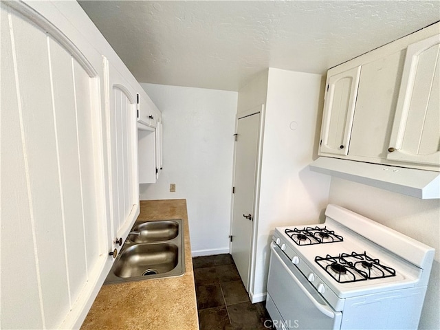 kitchen with white gas stove, white cabinetry, sink, and a textured ceiling