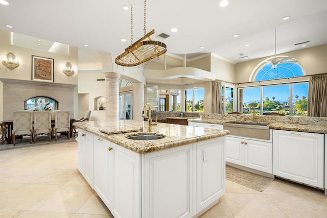 kitchen with a center island with sink, a wealth of natural light, sink, and light stone countertops