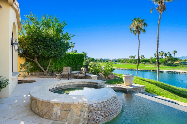 view of swimming pool featuring a yard, an in ground hot tub, a water view, and a patio area