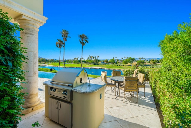 view of patio / terrace with a water view, an outdoor kitchen, and grilling area