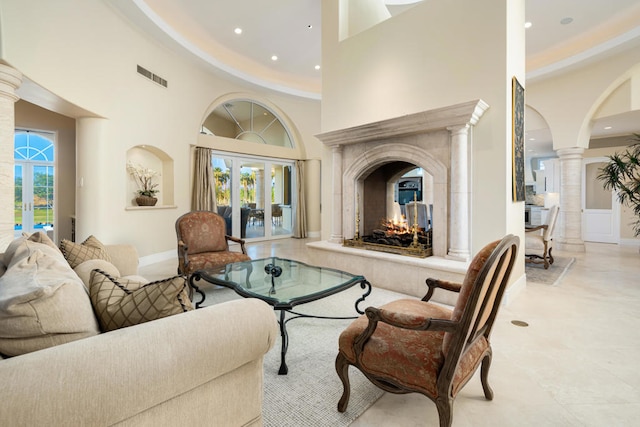 living room featuring a high ceiling, french doors, and ornate columns