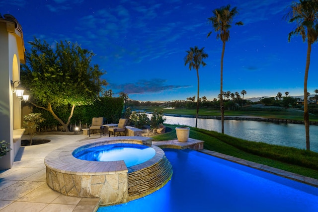 pool at dusk with a patio, a water view, and an in ground hot tub