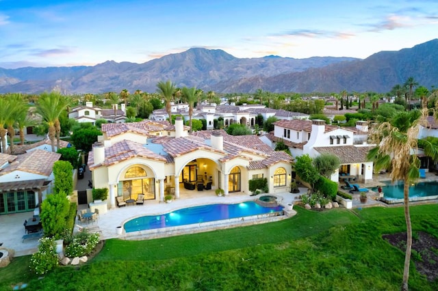 rear view of property featuring a patio, a yard, and a mountain view