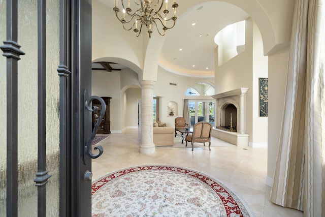 foyer with a towering ceiling, decorative columns, and light tile patterned flooring