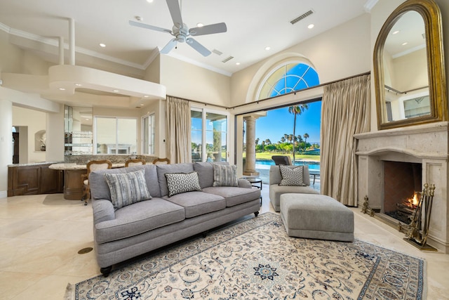 tiled living room featuring a high ceiling, a premium fireplace, ceiling fan, and crown molding