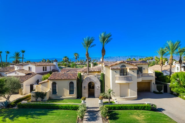 mediterranean / spanish house featuring a balcony and a front lawn