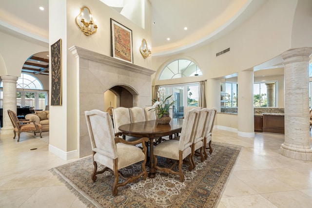 tiled dining area with a towering ceiling, decorative columns, and french doors