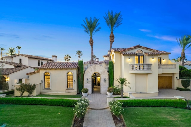 mediterranean / spanish-style house with a balcony and a yard