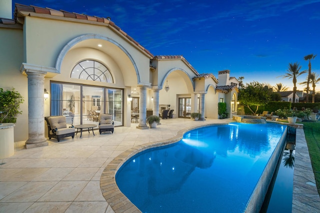 pool at dusk with a patio area