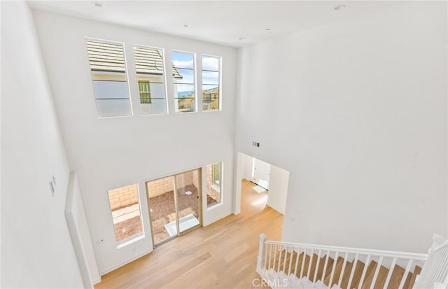 stairway with hardwood / wood-style floors and a towering ceiling