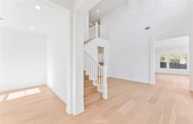 stairway with wood-type flooring and a towering ceiling