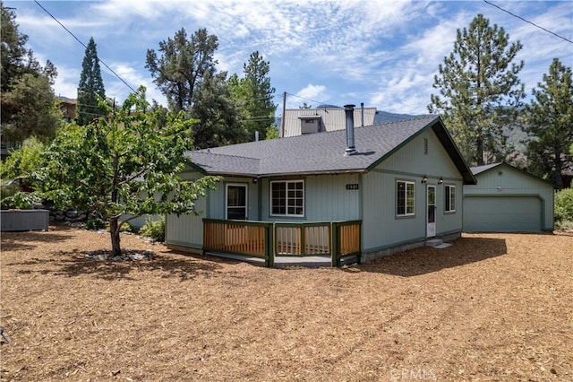 back of house with a garage, an outdoor structure, and a deck