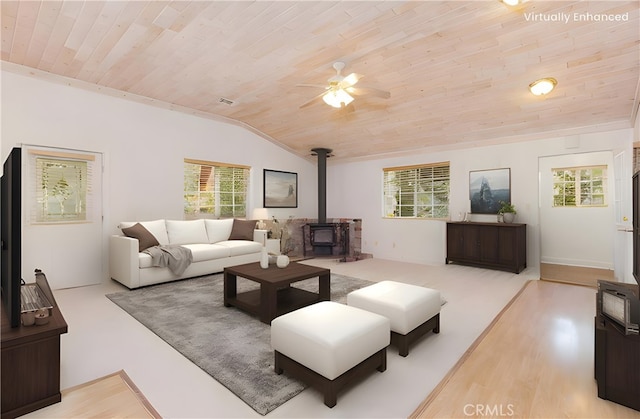 living room featuring wood ceiling, light hardwood / wood-style flooring, a healthy amount of sunlight, and a wood stove