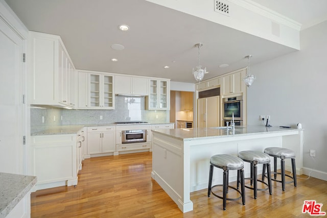 kitchen with backsplash, white cabinetry, light hardwood / wood-style flooring, and stainless steel appliances