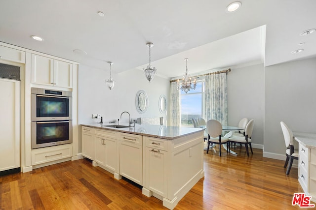 kitchen featuring appliances with stainless steel finishes, hardwood / wood-style floors, sink, and hanging light fixtures