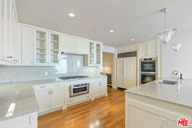 kitchen with sink, white cabinets, hanging light fixtures, light hardwood / wood-style flooring, and appliances with stainless steel finishes