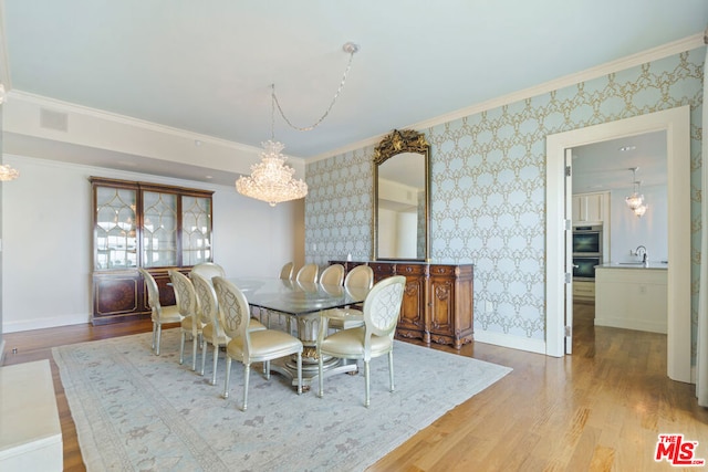 dining space featuring crown molding, hardwood / wood-style floors, sink, and a notable chandelier