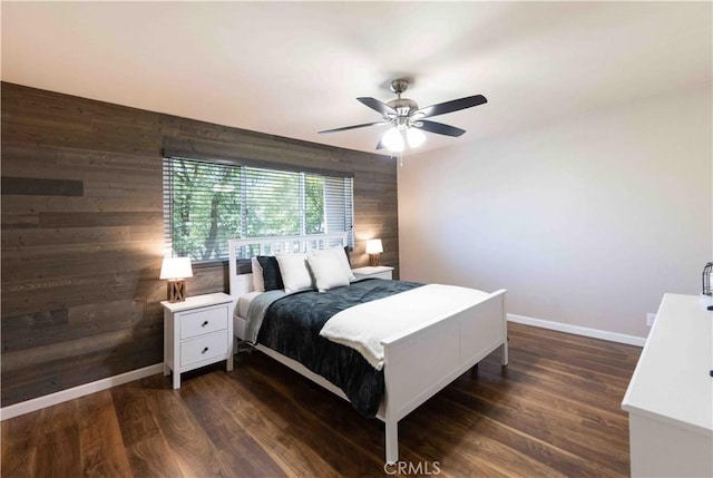 bedroom featuring ceiling fan, wood walls, and dark wood-type flooring