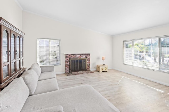 living room with ornamental molding, plenty of natural light, light wood-type flooring, and a brick fireplace