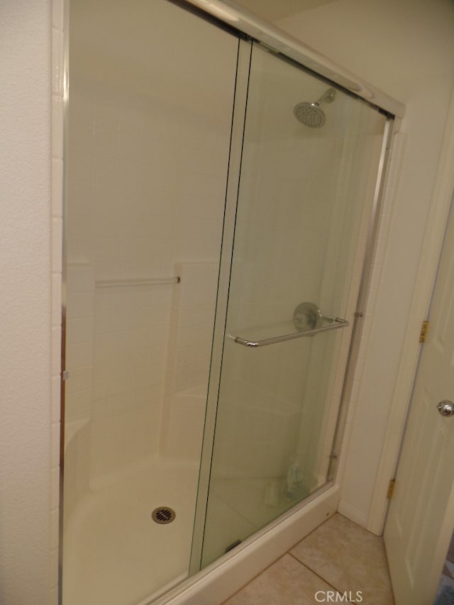 bathroom with a shower with shower door and tile patterned flooring