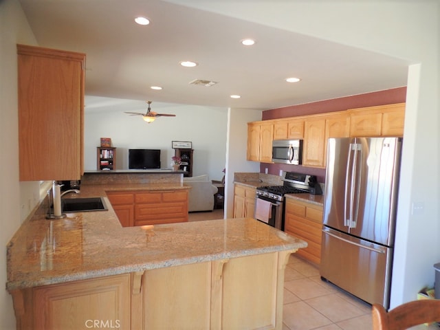 kitchen with kitchen peninsula, stainless steel appliances, light brown cabinetry, ceiling fan, and sink