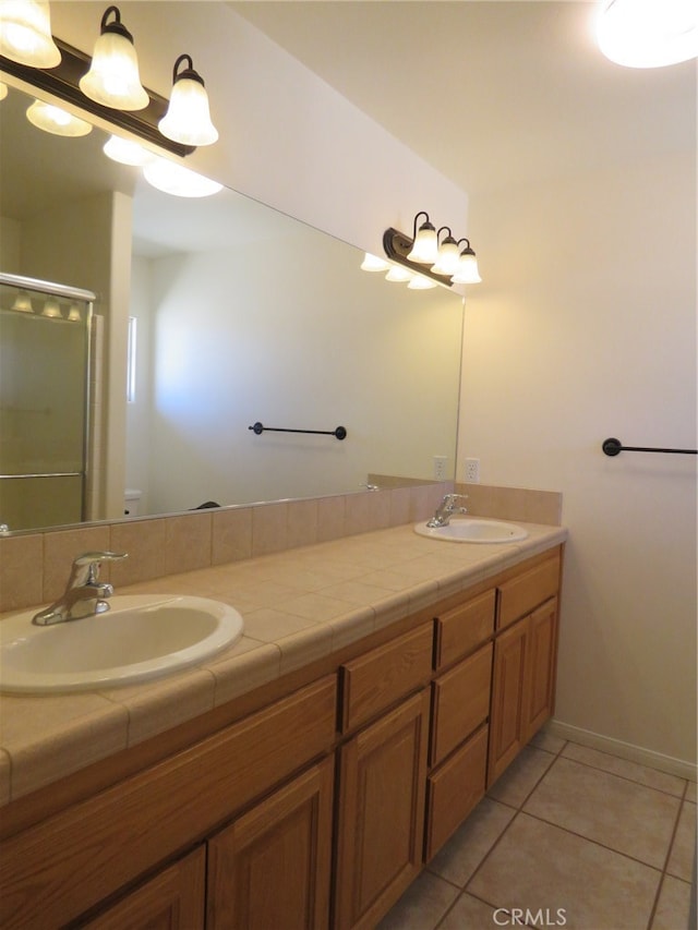 bathroom with a shower with door, vanity, and tile patterned floors