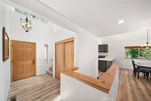 foyer entrance with vaulted ceiling, a chandelier, and hardwood / wood-style flooring